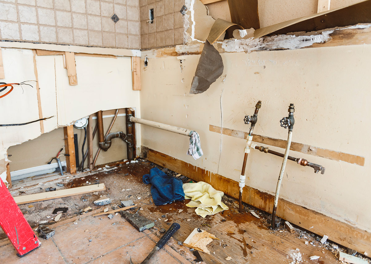 Upper Marlboro MD Water Damage Restoration by Triangle Legacy: Demolition phase showing damaged walls, exposed pipes, and floor.